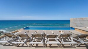 A poolside area with lounge chairs and a view of the ocean.