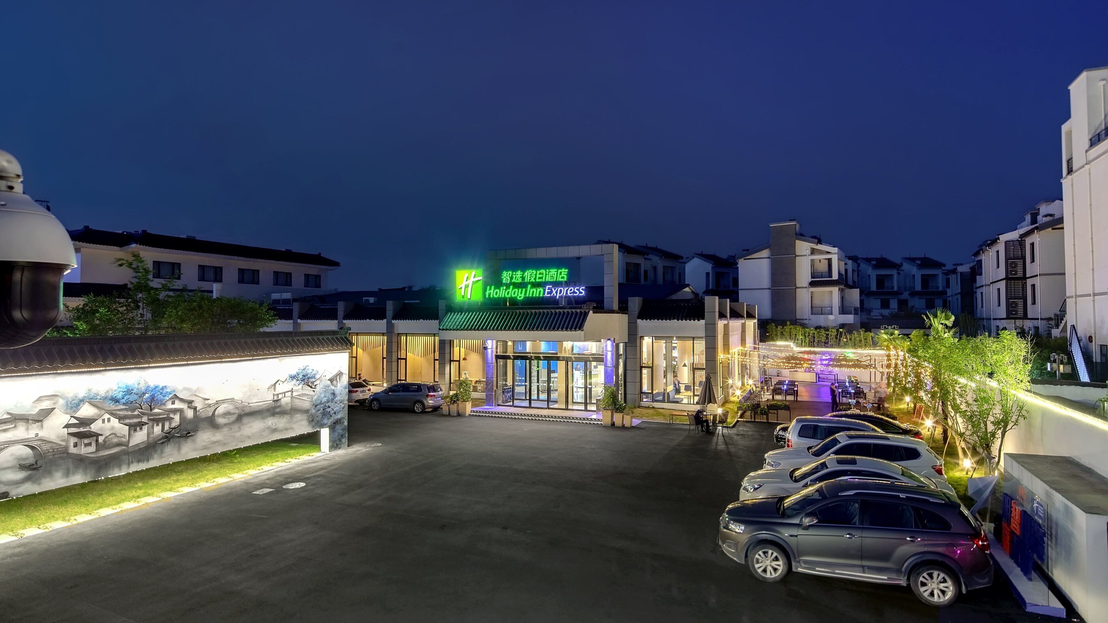 Un hotel Holiday Inn Express con un estacionamiento y un mural en la pared.