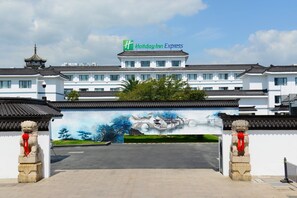 A Holiday Inn Express hotel with traditional Chinese architectural elements and a mural of a scenic landscape. - Holiday Inn Express Suzhou Zhouzhuang Ancient Town by IHG (Suzhou)