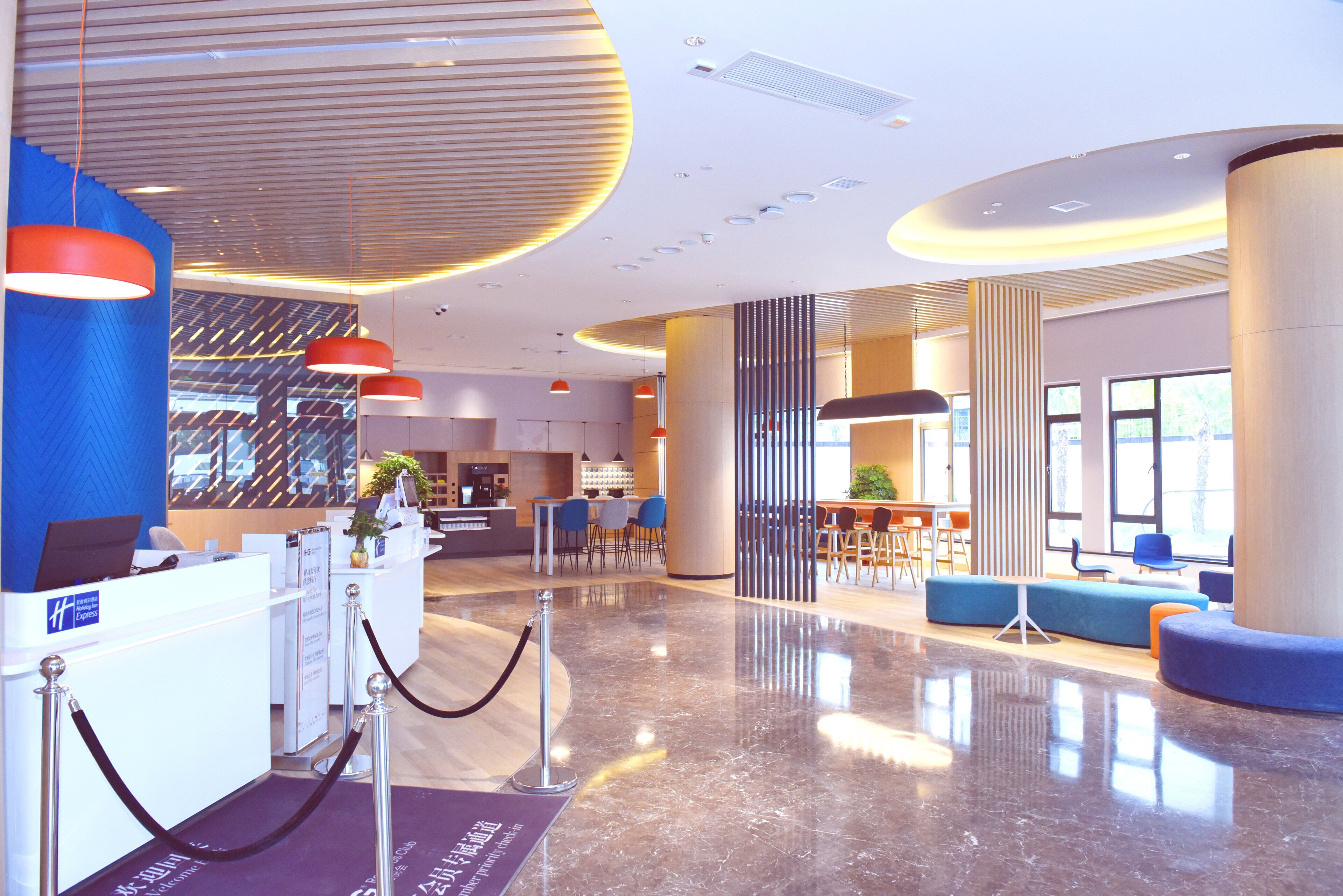Un moderno vestíbulo de hotel con mostrador de recepción, zonas de estar y un mostrador de registro.