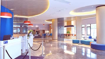 Un moderno vestíbulo de hotel con mostrador de recepción, zonas de estar y un mostrador de registro.