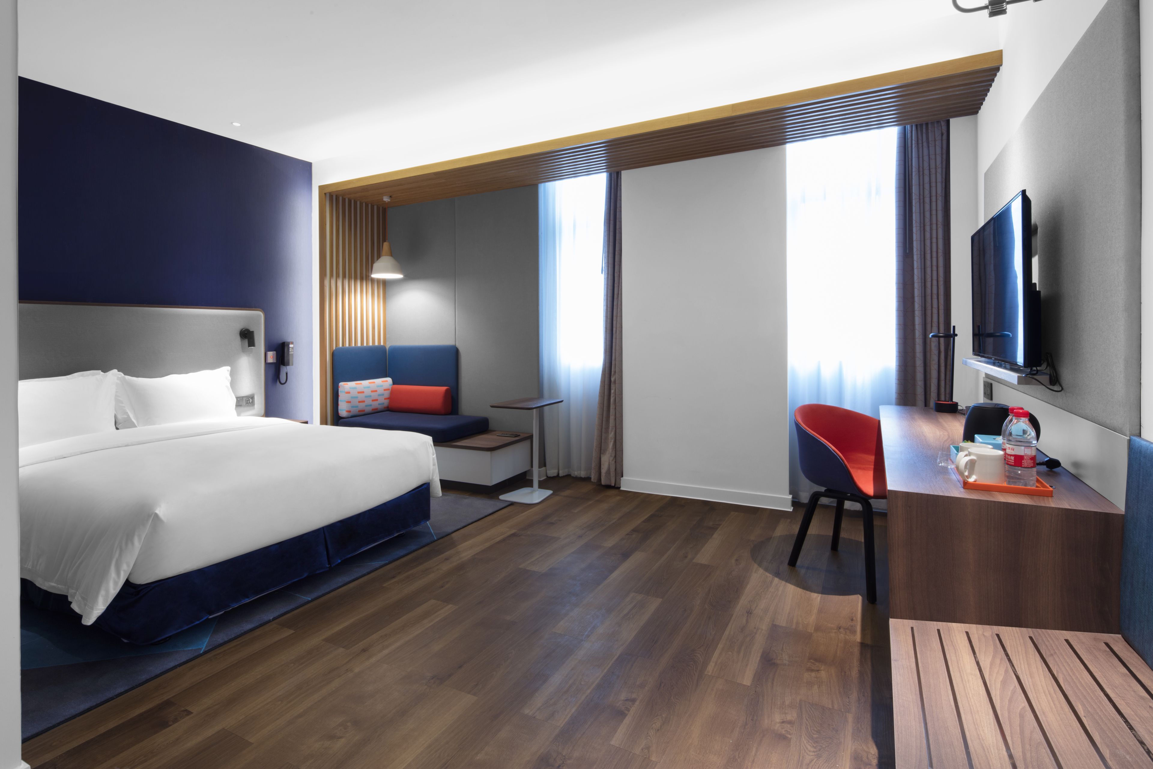 Una habitación de hotel moderna con una cama grande, un escritorio, una silla y un televisor.