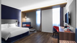 Une chambre d’hôtel moderne équipée d’un grand lit, d’un bureau, d’une chaise et d’un téléviseur.