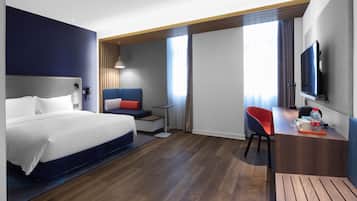 Una habitación de hotel moderna con una cama grande, un escritorio, una silla y un televisor.