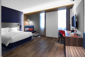 Een moderne hotelkamer met een groot bed, een bureau, een stoel en een televisie.