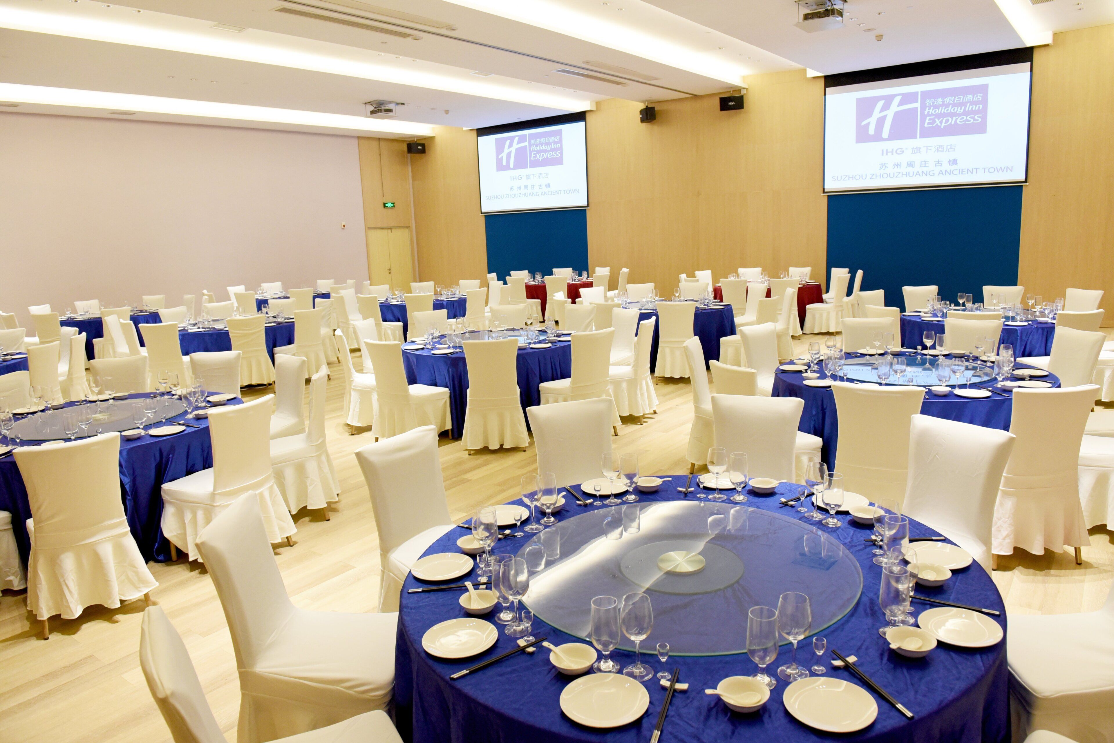 A conference room with round tables set for a formal event, equipped with nameplates, plates, and glasses.