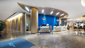 Un hall d’hôtel moderne comprenant un comptoir d’accueil, un espace salon et un bar.