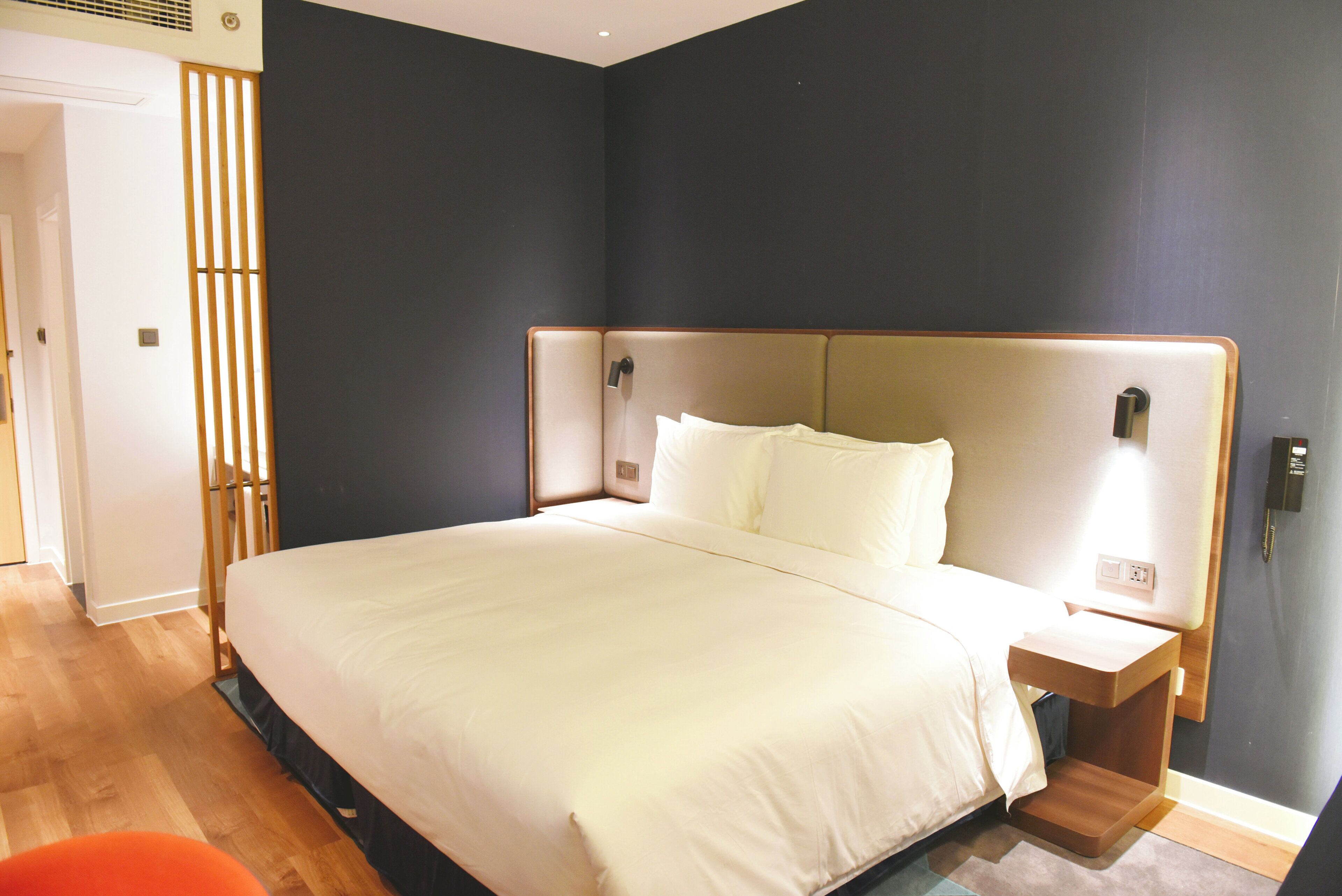 Una habitación de hotel con una cama grande, mesitas de noche y suelo de madera.