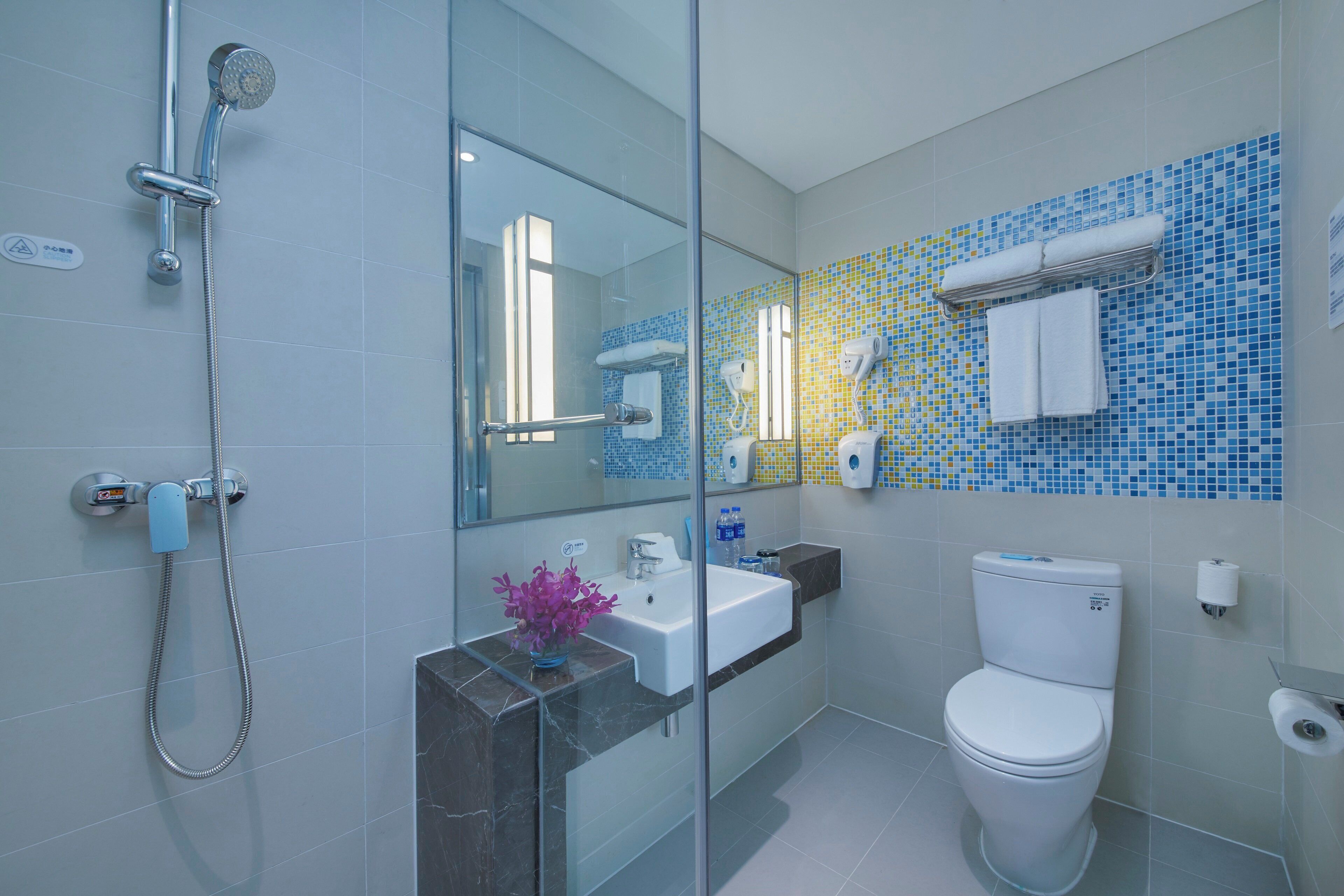 Un baño moderno con cabina de ducha de vidrio, un lavabo blanco, un inodoro y un espejo.