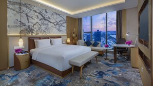 Een moderne hotelkamer met een groot bed, een bureau en uitzicht op de stad.