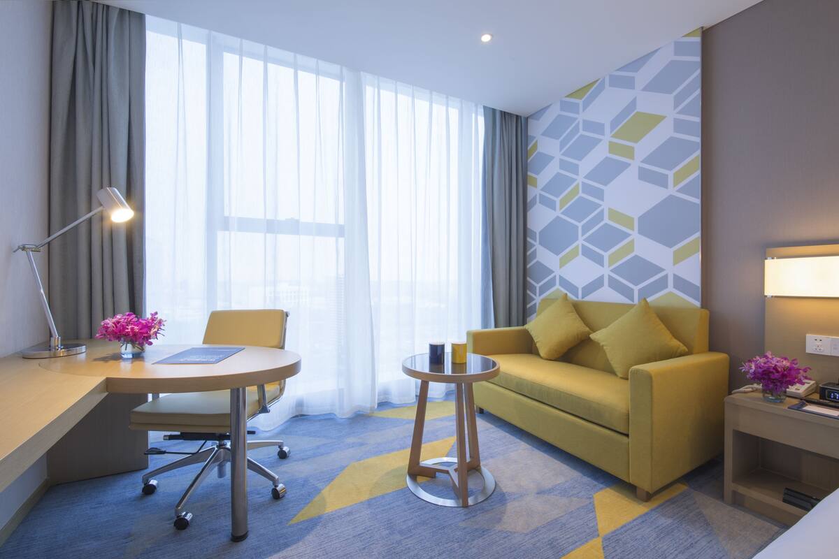 Une chambre d’hôtel équipée d’un bureau, d’une chaise, d’un canapé et d’une petite table ronde.
