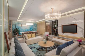 Un salon moderne avec un lustre, un canapé, une table basse et un téléviseur à écran plat fixé au mur.