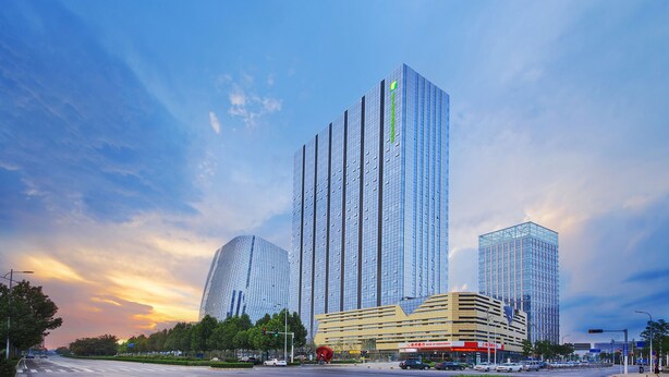 Een moderne stedelijke skyline met hoge gebouwen, een opvallende gebogen constructie en een bedrijfsgebouw met een gele gevel.
