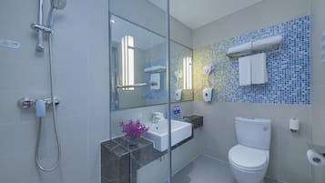 Un baño moderno con cabina de ducha de vidrio, un lavamanos blanco y un inodoro.