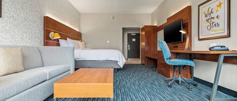 A hotel room with a bed, a sofa, a desk, and a chair.
