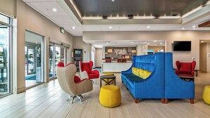 Un vestíbulo espacioso con muebles modernos, un mostrador de recepción y una pantalla de televisión grande.