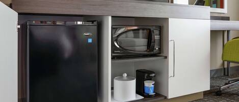 A compact kitchenette with a refrigerator, microwave, and coffee maker.