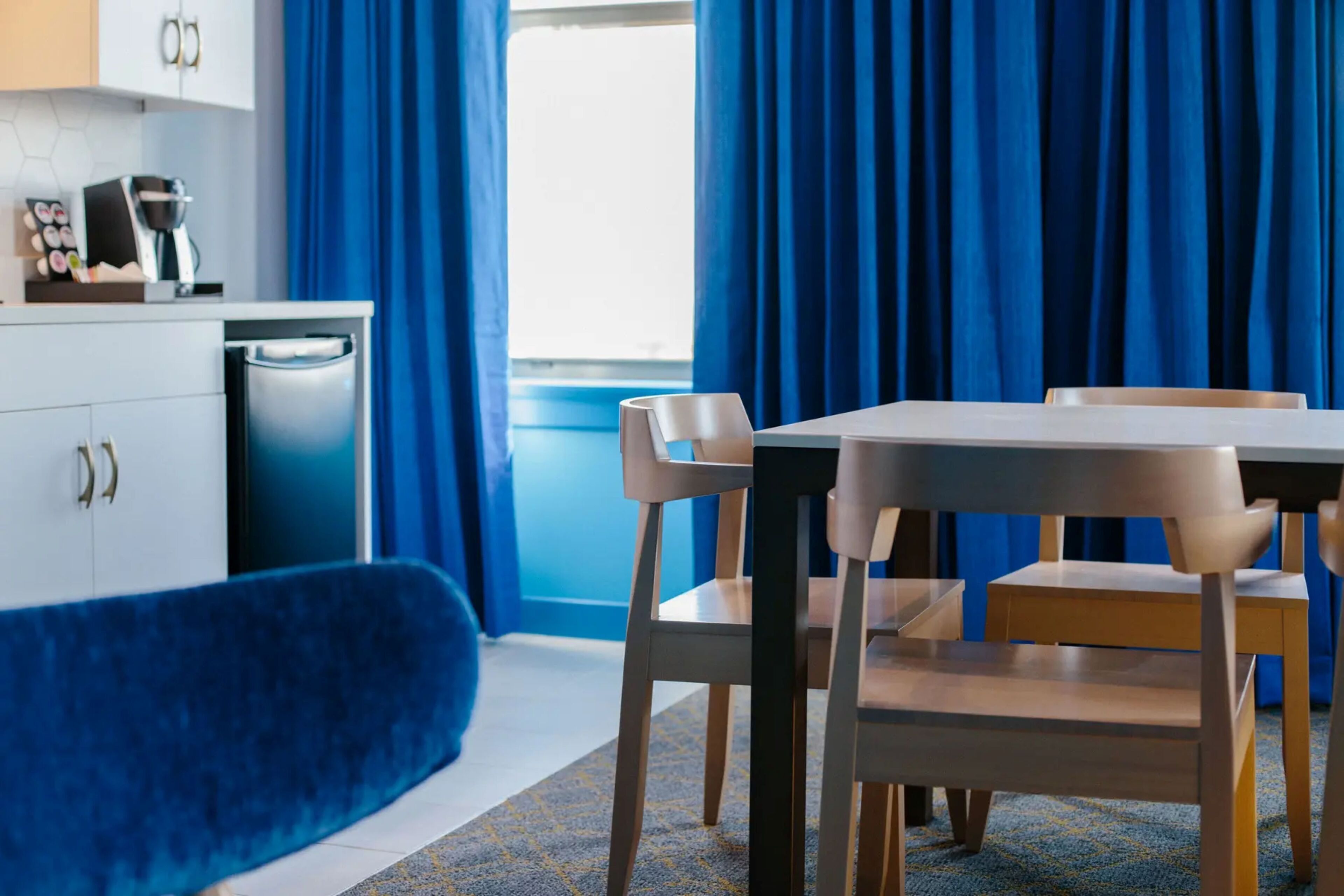 Una habitación moderna con comedor, sofá y área de cocina con cafetera.