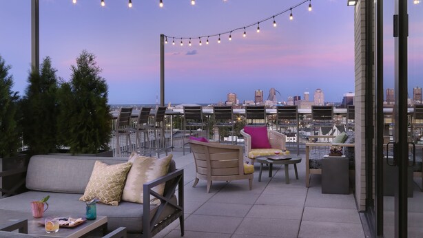 A rooftop terrace with outdoor seating, string lights, and a city skyline view. - Angad Arts Hotel St. Louis, Tapestry Collection by Hilton (St. Louis)