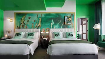 Habitació d'hotel amb dos llits, un mural a la paret amb motius verds i un disseny modern.