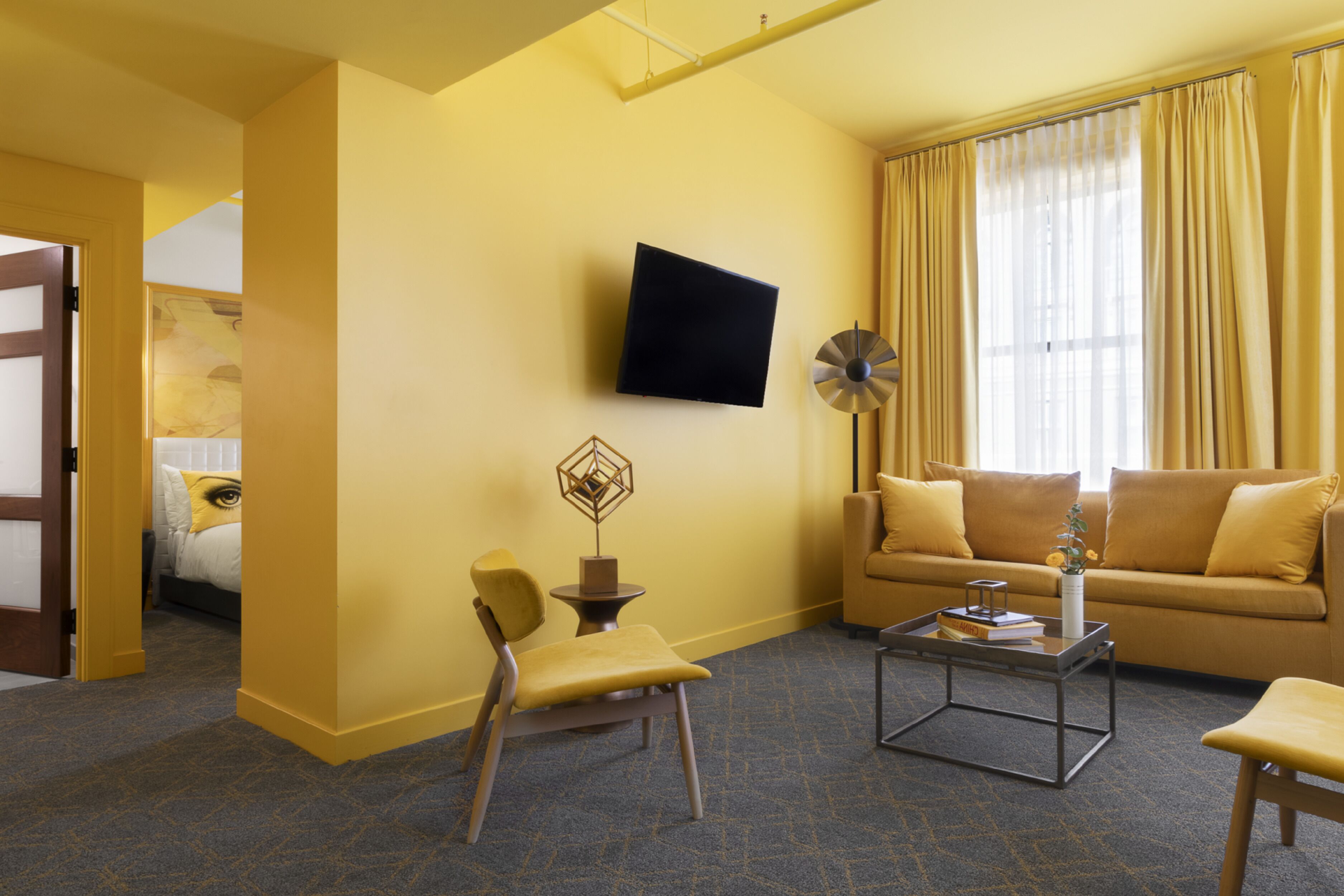 A living room with a sofa, armchairs, a coffee table, a flat-screen TV, and a decorative item on the wall.