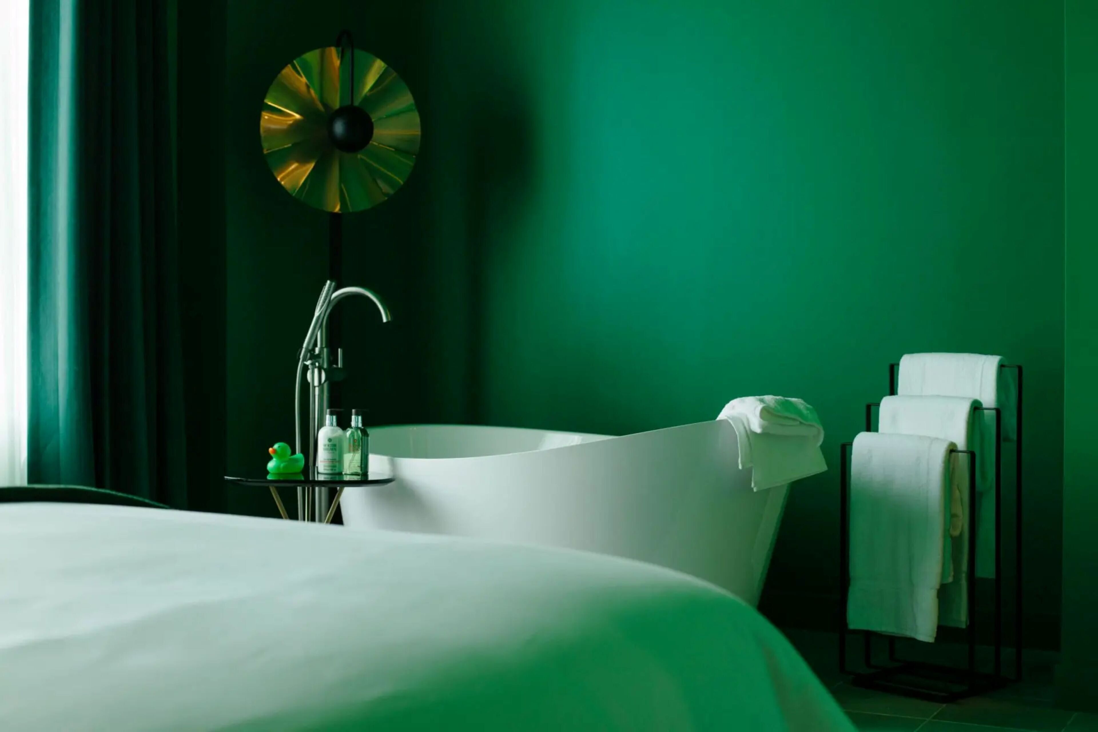 Una habitación de hotel moderna con una cama grande, una bañera independiente y un perchero para toallas.