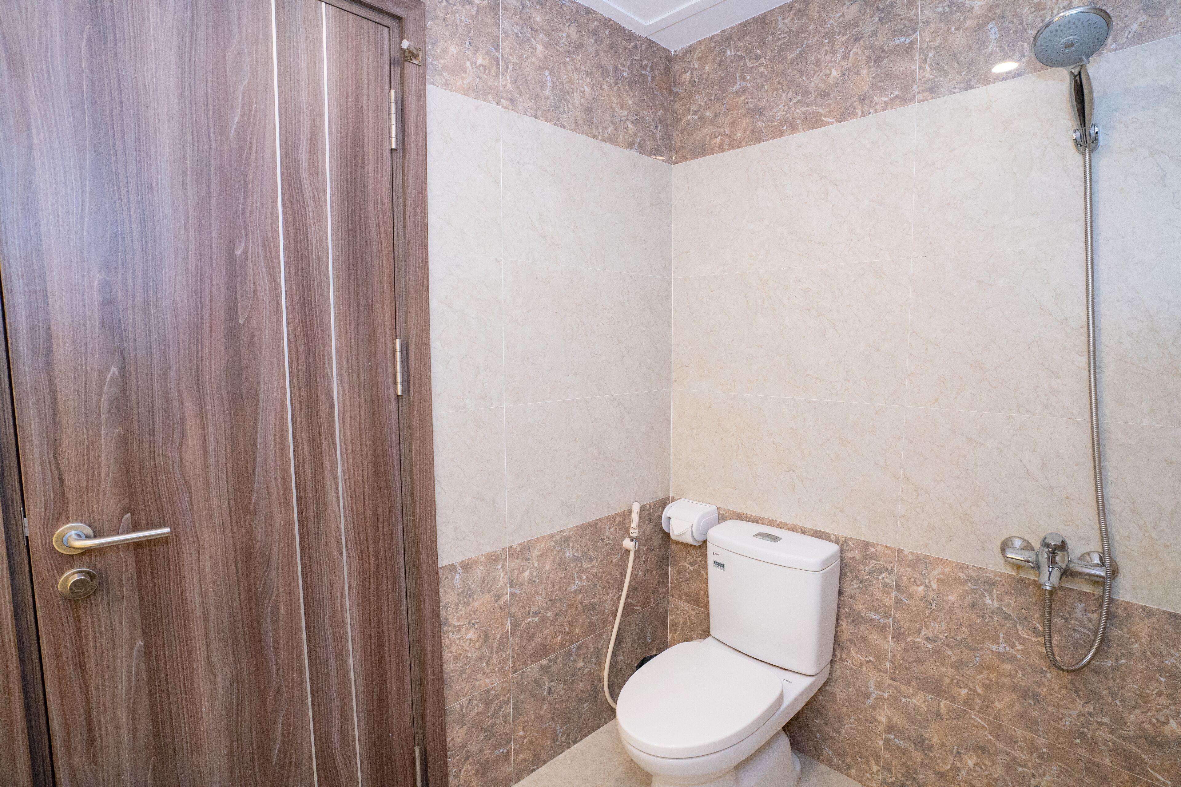 A bathroom with a wooden door, a toilet, and a shower.