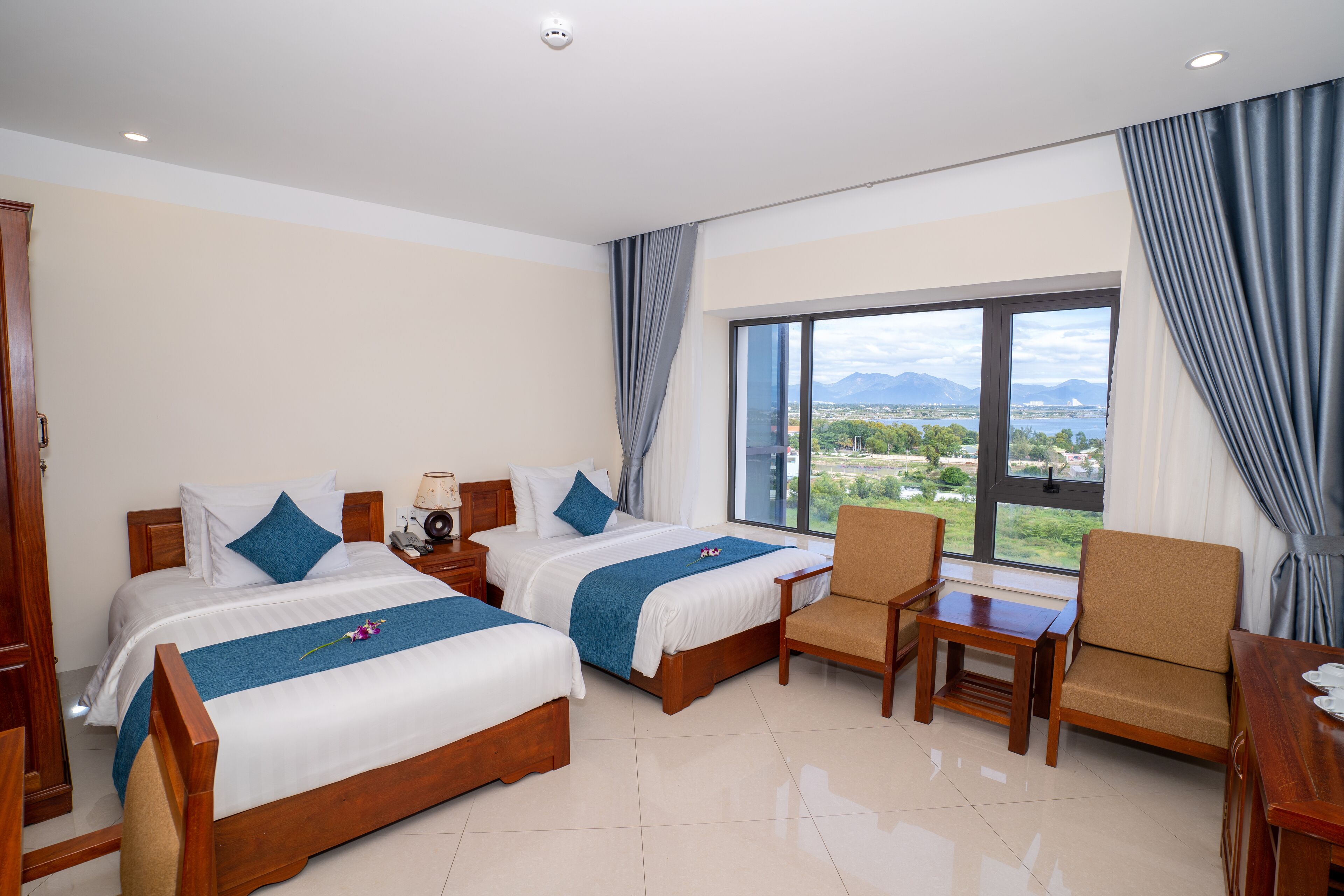 Ein Hotelzimmer mit zwei Betten, einer Sitzecke und einem großen Fenster mit Blick auf die Landschaft.