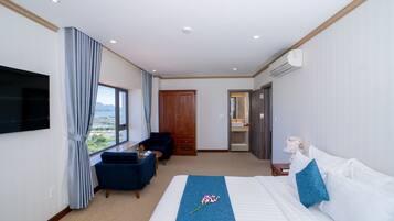 A hotel room with a bed, a TV, a desk, a chair, and a window with a view.