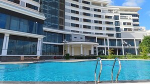 Un hotel modern amb piscina, finestres grans i una estructura de diversos pisos.