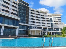 Una piscina al aire libre, sombrillas, sillones reclinables de piscina