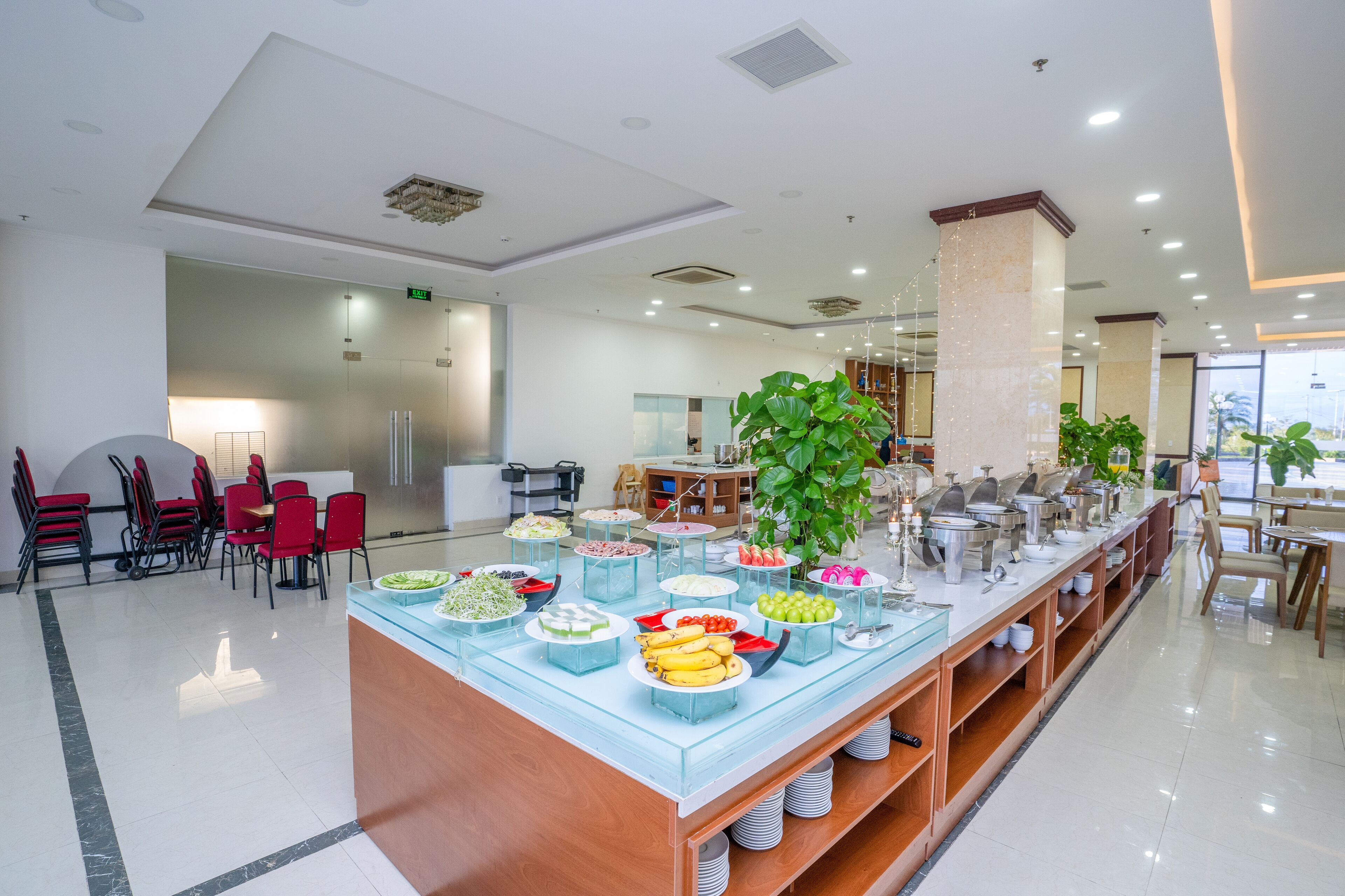 A buffet area with various food items and a seating arrangement with red chairs.