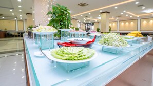Buffet amb diferents plats i una gran planta en test.