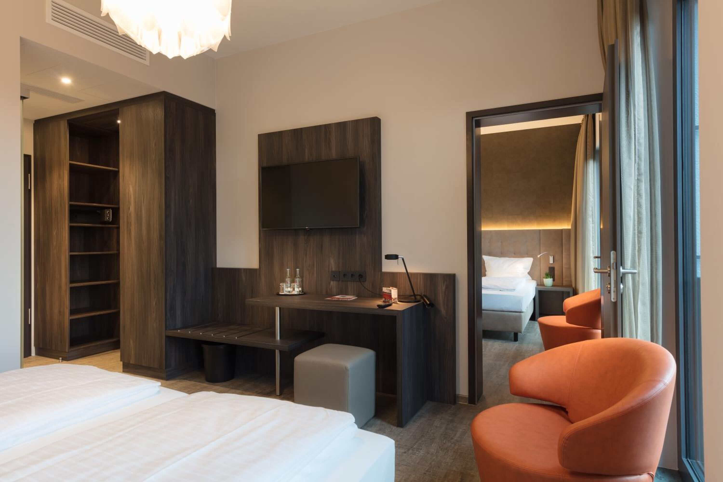 Habitación de hotel con cama, escritorio, silla, televisor y armario.