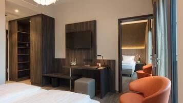 A hotel room with a bed, a desk, a chair, a TV, and a wardrobe.