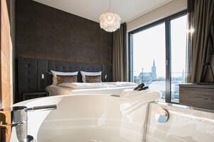 Una habitación de hotel moderna con una cama grande, una bañera y vistas a la ciudad desde la ventana.