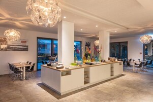 Un moderno vestíbulo de hotel con un mostrador de recepción central, zona de estar y elementos decorativos.