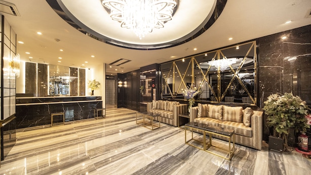 A modern lobby with a marble floor, a reception desk, a sofa, and a chandelier. - The Grandeur Hotel (Kawasaki)