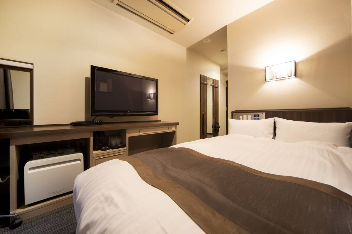 Une chambre d’hôtel équipée d’un lit, d’une télévision, d’un bureau et d’un miroir.