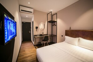 Een hotelkamer met een bed, bureau, stoel, televisie en spiegel.