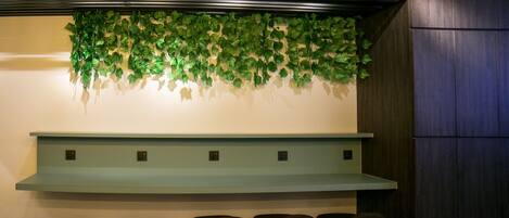 A bar area with a light blue counter, four stools, hanging light bulbs, and a green leafy wall decoration.