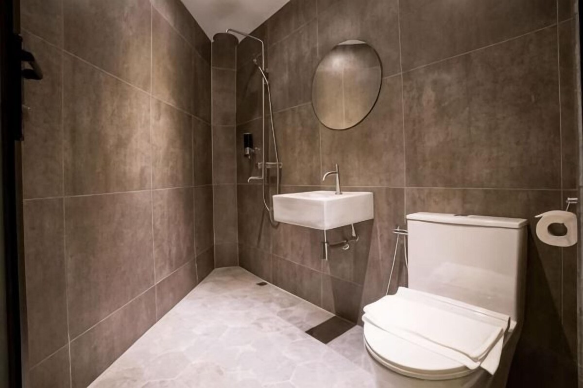 A bathroom with a shower, sink, toilet, and a mirror.