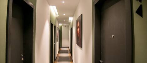 A hotel hallway with doors on both sides, a carpeted floor, and recessed lighting.