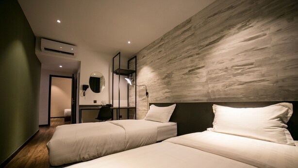 Une chambre d’hôtel avec deux lits, un bureau, une chaise, un miroir et un appareil de climatisation.