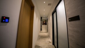 Un couloir avec une porte en bois, un écran numérique, un mur en marbre et une œuvre d’art encadrée.