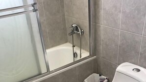 A bathroom with a shower, toilet, and a small trash bin. - Residencial Mia Molina (Puñal)