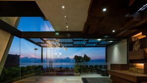 Uma área de recepção moderna com parede de vidro que oferece vista para montanhas e um pôr do sol.