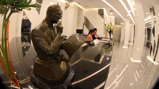 A lobby with a polished black reception desk, a statue, and a modern interior design. - K.S. Pavilion Hotel (Nakhon Ratchasima)