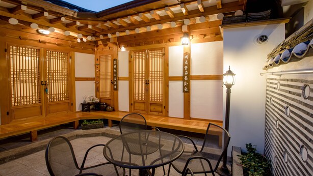Una habitació tradicional japonesa amb fons de tatami, una taula de fusta baixa amb cadires i un farol.