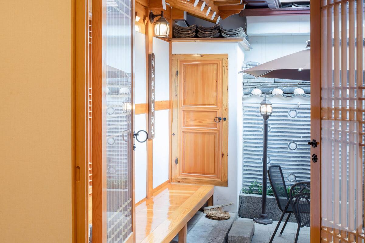 A traditional Japanese room with tatami flooring, a wooden door, and a sliding glass door leading to a balcony.